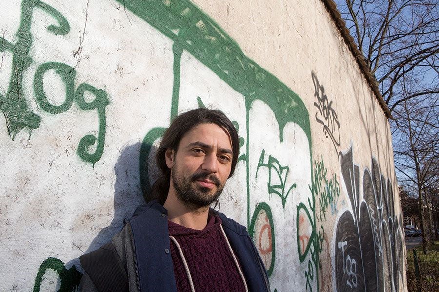 Muhannad Qaiconie stands by the remains of part of the Berlin Wall, which divided the city during the cold war. He and a friend migrated from Syria several years ago to escape the violence. Both were granted asylum. Mr. Qaiconie now attends college. (Melanie Stetson Freeman/Staff)