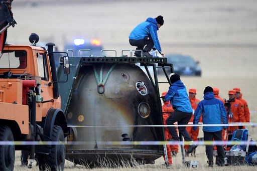 In this photo released by Xinhua News Agency, ground crew check on the re-entry capsule of Shenzhou 11 spacecraft after it landed in north China's Inner Mongolia Autonomous Region, Friday, Nov. 18, 2016. A pair of Chinese astronauts returned Friday from a monthlong stay aboard the country's space station, China's sixth and longest crewed mission and a sign of the growing ambitions of its rapidly advancing space program. (Ren Junchuan/Xinhua via AP)
