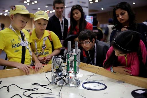 In this Sunday, Nov. 27, 2016 photo, participants and spectators look at a 3D printer made of LEGO parts during the World Robot Olympiad in New Delhi, India. The weekend games brought more than 450 teams of students from 50 countries to the Indian capital. (AP Photo/Tsering Topgyal)