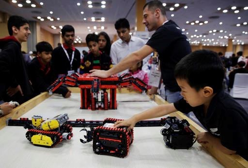In this Sunday, Nov. 27, 2016, photo, a boy plays with a robot during the World Robot Olympiad in New Delhi, India. The weekend games brought more than 450 teams of students from 50 countries to the Indian capital. (AP Photo/Tsering Topgyal)