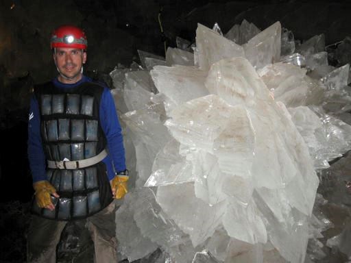In this image provided by Mike Spilde, Mario Corsalini stands near to a gypsum rosette crystal. In a Mexican cave system so beautiful and hot that it is called both Fairyland and hell, scientists have discovered life trapped in crystals that could be 50,000 years old. The bizarre and ancient microbes were found dormant in caves in Naica, Mexico, and were able to exist by living on minerals such as iron and manganese, said Penelope Boston, head of NASA's Astrobiology Institute. (Mike Spilde via AP)