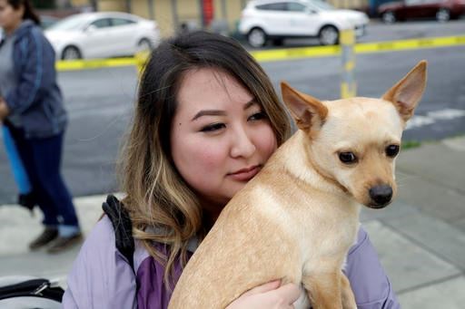 Diana Pham hugs her dog after being rescued by boat from a flooded neighborhood Tuesday, Feb. 21, 2017, in San Jose, Calif. Rescuers chest-deep in water steered boats carrying dozens of people, some with babies and pets, from a San Jose neighborhood inundated by water from an overflowing creek Tuesday. (AP Photo/Marcio Jose Sanchez)