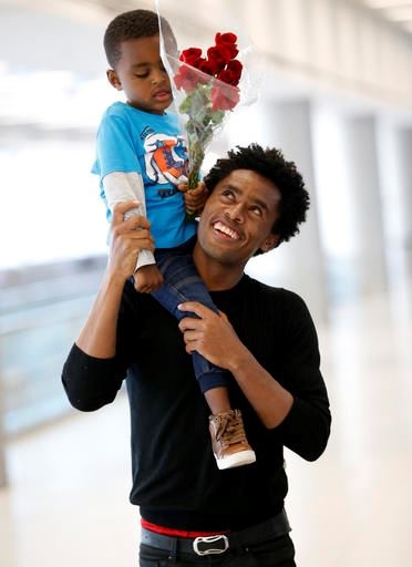 Olympic silver medalist Feyisa Lilesa, holds his son Sora, 3, while picking up his family at Miami International Airport, Tuesday, Feb. 14, 2017, in Miami. Lilesa arrived in the U.S. on a special skills visa, which allows him to train and compete until January. His wife, son, daughter and brother joined him in Miami Tuesday. (AP Photo/Wilfredo Lee)