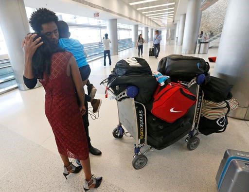Olympic silver medalist Feyisa Lilesa, of Ethiopia, hugs his wife Iftu Mulia, and his son Sora, 3, while picking up his family at Miami International Airport, Tuesday, Feb. 14, 2017, in Miami. Lilesa arrived in the U.S. on a special skills visa, which allows him to train and compete until January. His wife, son, daughter and brother joined him in Miami Tuesday. (AP Photo/Wilfredo Lee)