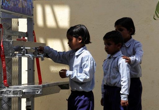 Schoolchildren line up to drink water from a newly set up water filtration tower at their school in Nai Basti Village, some 55 kilometers (35 miles) from in New Delhi, India, Wednesday, March 22, 2017. Schoolchildren cheered and village women clapped as a gush of clean water flowed through a set of gleaming steel taps connected to a newly installed water filtration plant in a dusty north Indian village on Wednesday. (AP Photo/Manish Swarup)