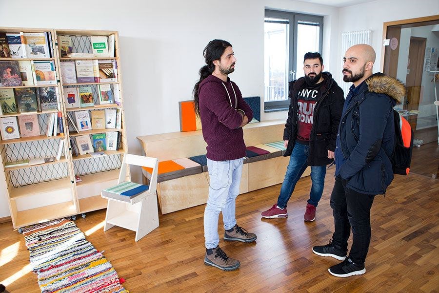 Muhannad Qaiconie chats with fellow Syrian migrants in the Arabic library he helped create to support new arrivals to Germany. (Melanie Stetson Freeman/Staff)