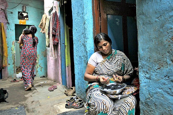 Shobha Vakade, who took a loan of rupees 18,000 ($400) from a microfinance company to start her own business, strings beads into necklaces outside her house in a slum in Mumbai, India. Microloan groups are expanding to include other services to clients, including savings accounts and health and education services. <P>Danish Siddiqui/Reuters/File