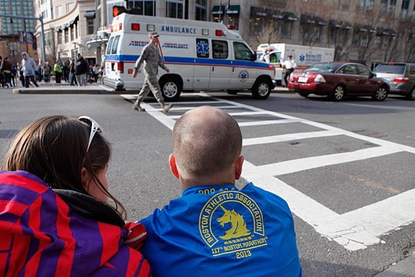 A couple sits on the sidewalk at an intersection where police have closed the road because of another bomb scare at a nearby hotel, on Monday in Boston, Massachusetts. All along the marathon route spectators came to the aid of runners offering drinks, blankets, cell phone calls, and even taking runners into their homes. <P>Melanie Stetson Freeman/TCSM