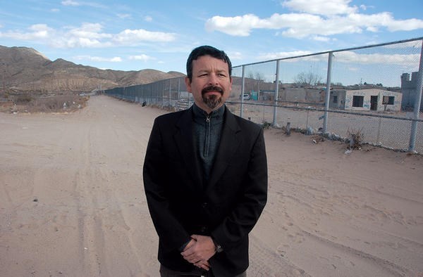 Fernando Garcia, director of the Border Network for Human Rights in El Paso, Texas, stands in front of the US-Mexican border fence.  <P>Tom A. Peter