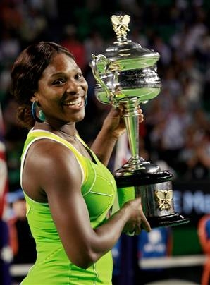 Serena Williams smiling while holding a trophy. (http://abagond.files.wordpress.com/2007/12/serena18.jpg)