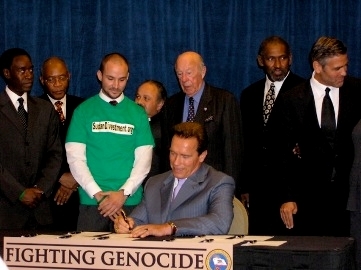 California Governor Schwarzenegger  signing the bill into law, with Sterling, Clooney, and Cheadle present.