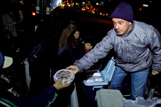 Muñoz dando comida en "su esquina" (NY Daily News)